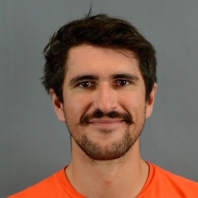 Pierrick Deniel, portrait photo on a grey background, orange t-shirt